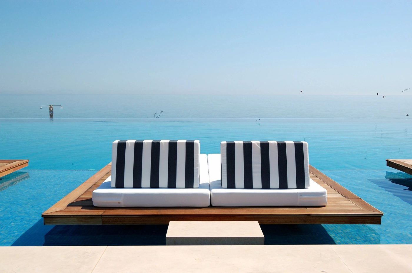 Striped loungers beside an infinity pool overlooking the sea