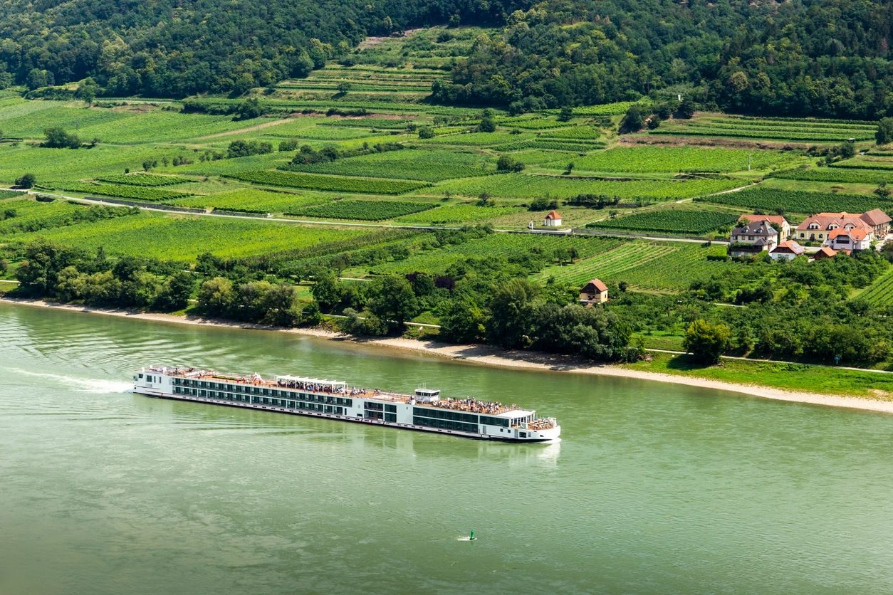A river cruise ship sailing past vineyards on the Danube